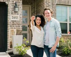 Couple standing in front of a home holding keys Ready to buy